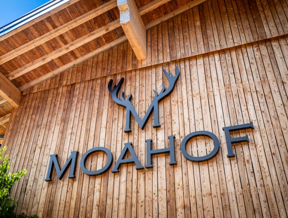Au&szlig;enfassade aus Holz am Moahof in Werfenweng mit Logo-Beschriftung.
